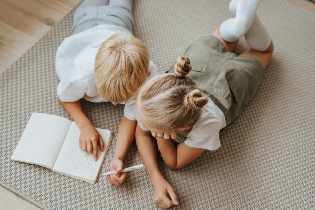 Two kids writing in a book